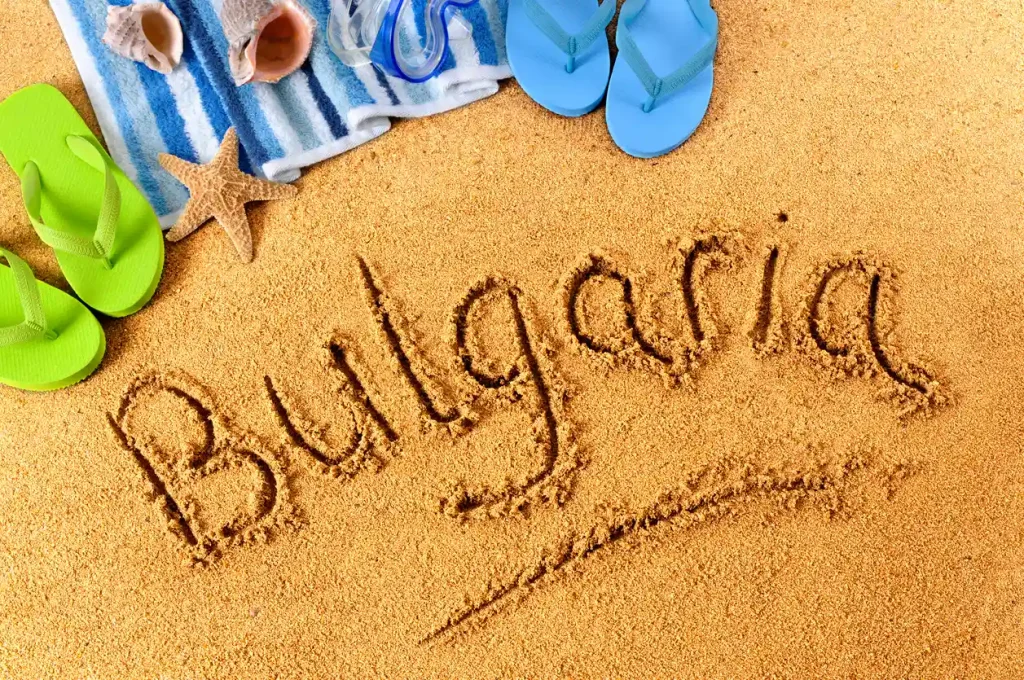 Bulgarije geschreven in zand, flip-flops en handdoek op het strand.